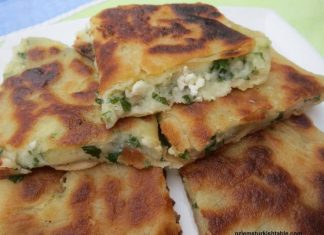 Τηγανητό πατατέλι με τυρί, κομμένο στη μέση, που φαίνεται η γέμιση πατάτας, φέτας και μαϊντανού.