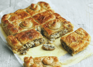 Μια ολόκληρη, χρυσαφένια ψημένη μανιταρόπιτα με σφολιάτα, κομμένη σε τετράγωνα, με την γέμιση να διακρίνεται.