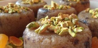 Ένα μπολ με χαλβά σιμιγδαλένιο, με καφέ χρώμα και ψιλοκομμένα καρύδια στην επιφάνεια.