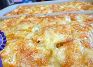 Ένα ψημένο χρυσαφένιο τυρόψωμο μέσα σε ταψί με εμφανή κομμάτια φέτας και αρωματική υφή