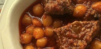 Μια κατσαρόλα με παραδοσιακό στιφάδο μοσχάρι, baby κρεμμυδάκια και πυκνή κόκκινη σάλτσα, γαρνιρισμένο με ξύλο κανέλας