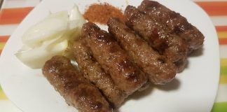 Καλοψημένα κεμπάπ πάνω σε πίτες, γαρνιρισμένα με ψιλοκομμένο κρεμμύδι, μαϊντανό και κόκκινο μπούκοβο.