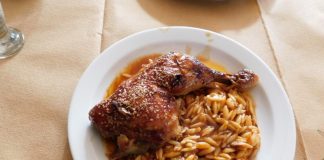 Ένα πιάτο γιουβέτσι με κοτόπουλο και κριθαράκι σε κόκκινη σάλτσα, πασπαλισμένο με τριμμένη φέτα.