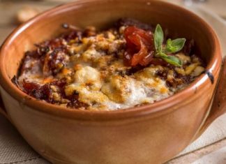 Ατομικά κεραμικά μπολάκια με στρώσεις ψωμιού τυριών και πλούσιας σάλτσας ντομάτας με κρεμμύδια ροδοκοκκινισμένα στον φούρνο