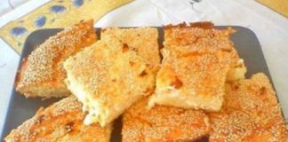 Κομμάτια αφράτης, χρυσαφένιας τυρόπιτας πασπαλισμένης με σουσάμι, σε ένα πλατο, με την υφή του γιαουρτιού και της φέτας να διακρίνεται.