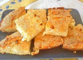 Κομμάτια αφράτης, χρυσαφένιας τυρόπιτας πασπαλισμένης με σουσάμι, σε ένα πλατο, με την υφή του γιαουρτιού και της φέτας να διακρίνεται.