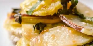 Πατάτες Φούρνου με Κολοκυθάκια και Κατσικίσιο Τυρί Ένα πιάτο γεμάτο ομοιόμορφα κομμένες φέτες πατάτας και κολοκυθιού, ψημένες μέχρι να ροδίσουν, με λιωμένο τυρί από πάνω.