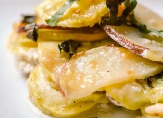 Ταψί με χρυσαφένιες ψητές πατάτες και κολοκυθάκια σε στρώσεις, με λιωμένο κατσικίσιο τυρί και παρμεζάνα στην επιφάνεια, πασπαλισμένο με φρέσκο βασιλικό.