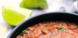 Ένα μπολ γεμάτο φρέσκια, χοντροκομμένη κόκκινη σάλτσα ντομάτας με κομμάτια κρεμμυδιού και πράσινα μυρωδικά.