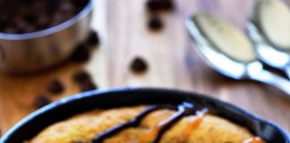 Ένα μικρό, ζεστό κέικ με λιωμένη σοκολάτα, σερβιρισμένο σε ένα πιάτο με μια μπάλα παγωτού βανίλιας από πάνω και περιχυμένο με σιρόπι σοκολάτας και καραμέλας.