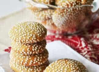 Στρογγυλά, επίπεδα μπισκότα καλυμμένα με σουσάμι, ψημένα μέχρι να πάρουν χρυσαφένιο χρώμα, τοποθετημένα σε ταψί με λαδόκολλα.