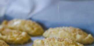 Ένα ταψί γεμάτο με , τυροπιτάκια σε σχήμα μισοφέγγαρου, πασπαλισμένα με σουσάμι.