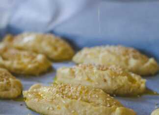 Ένα ταψί γεμάτο με , τυροπιτάκια σε σχήμα μισοφέγγαρου, πασπαλισμένα με σουσάμι.