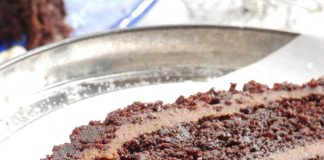 Ένα κομμένο κομμάτι από ένα πλούσιο κέικ σοκολάτας με στρώσεις παντεσπάνι και κρέμα σοκολάτας, πασπαλισμένο με ψίχουλα κέικ.