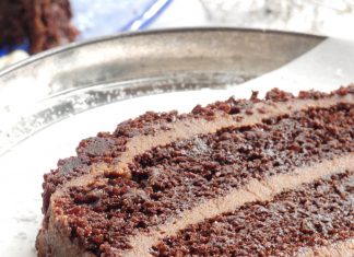 Ένα κομμένο κομμάτι από ένα πλούσιο κέικ σοκολάτας με στρώσεις παντεσπάνι και κρέμα σοκολάτας, πασπαλισμένο με ψίχουλα κέικ.