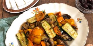 Μια ποικιλία από κομμένα λαχανικά (πιπεριές, κολοκυθάκια, μανιτάρια) σε ένα μπολ, καλυμμένα με ελαιόλαδο και μυρωδικά, έτοιμα για ψήσιμο.