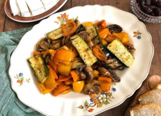 Μια ποικιλία από κομμένα λαχανικά (πιπεριές, κολοκυθάκια, μανιτάρια) σε ένα μπολ, καλυμμένα με ελαιόλαδο και μυρωδικά, έτοιμα για ψήσιμο.