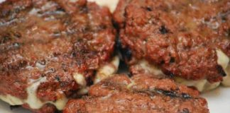 Ένα ζουμερό σπιτικό burger γεμιστό με λιωμένο τυρί σε σχάρα.