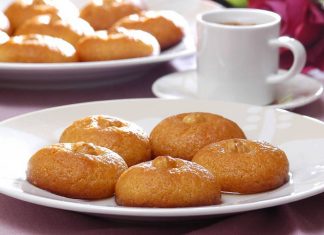 Σιροπιαστά χρυσαφένια κουλουράκια με σιμιγδάλι διακοσμημένα με ένα φουντούκι στο κέντρο τοποθετημένα σε πιατέλα