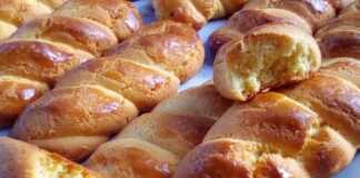 Σειρά από χρυσαφένια νηστίσιμα κουλουράκια πορτοκαλιού πάνω σε λαδόκολλα, γυαλισμένα και ευωδιαστά