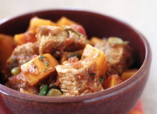 Χοιρινό κοκκινιστό σε βαθύ πιάτο, με τις πατάτες να έχουν μελώσει στην κόκκινη σάλτσα.