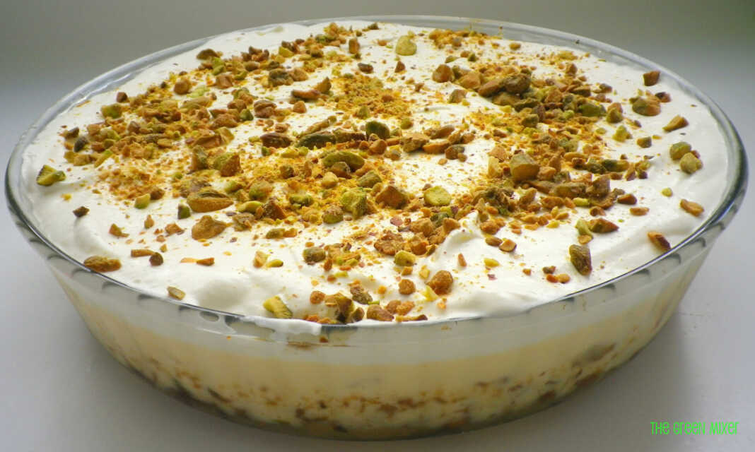 Ένα κομμάτι εκμέκ κανταΐφι σε ένα πιάτο, που δείχνει την τραγανή βάση κανταϊφιού, τη λευκή κρέμα και την στρώση σαντιγί πασπαλισμένη με πράσινα φιστίκια Αιγίνης.