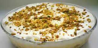 Ένα κομμάτι εκμέκ κανταΐφι σε ένα πιάτο, που δείχνει την τραγανή βάση κανταϊφιού, τη λευκή κρέμα και την στρώση σαντιγί πασπαλισμένη με πράσινα φιστίκια Αιγίνης.