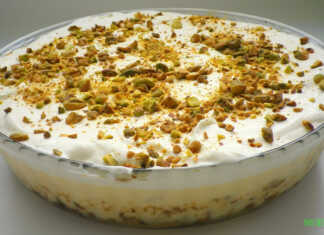 Ένα κομμάτι εκμέκ κανταΐφι σε ένα πιάτο, που δείχνει την τραγανή βάση κανταϊφιού, τη λευκή κρέμα και την στρώση σαντιγί πασπαλισμένη με πράσινα φιστίκια Αιγίνης.