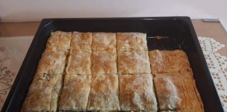 Ένα ταψί χρυσαφένιας, τραγανής σπανακοτυρόπιτας με ορατές στρώσεις φύλλου και πλούσια πράσινη γέμιση.