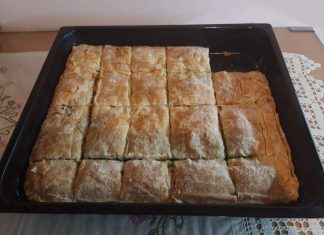 Ένα ταψί χρυσαφένιας, τραγανής σπανακοτυρόπιτας με ορατές στρώσεις φύλλου και πλούσια πράσινη γέμιση.