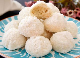 Χιονισμένα κουλουράκια με καρύδα, πασπαλισμένα πλούσια με άχνη ζάχαρη, σερβιρισμένα σε πιατέλα.