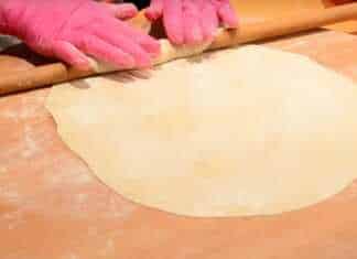 Ζύμη για πίτα, πιασμένη σε μπάλα, σκεπασμένη με πετσέτα για να ξεκουραστεί, μερικές μικρές μπάλες ζύμης δίπλα.