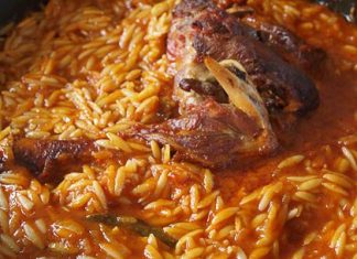 Ένα πιάτο με ζουμερό αρνάκι κοκκινιστό γιουβέτσι, με τρυφερό κρέας και κριθαράκι σε πλούσια κόκκινη σάλτσα, πασπαλισμένο με φρέσκο μαϊντανό και φέτα.