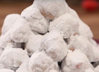 Κουραμπιέδες σε στρογγυλό σχήμα και σχήμα μισοφέγγαρου, τοποθετημένοι σε πιατέλα και πασπαλισμένοι με πλούσια στρώση ζάχαρης άχνης.