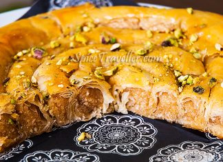 Ένα εντυπωσιακό σπειροειδές σιροπιαστό γλυκό σε σχήμα φιδιού πασπαλισμένο με φιστίκια Αιγίνης και αμύγδαλα που γυαλίζει από το σιρόπι μελιού