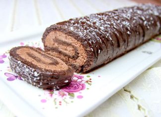 Ένα ολόκληρο κομμάτι Κορμός Σοκολάτας, περιχυμένο με γλάσο και πασπαλισμένο με καρύδα, σε ξύλινη επιφάνεια