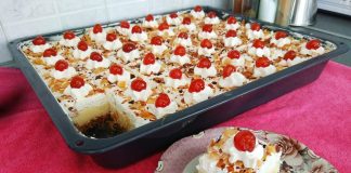 Ένα μεγάλο τετράγωνο ταψί με εκμέκ κανταΐφι, που δείχνει το χρυσαφένιο κανταΐφι στη βάση, μια παχιά στρώση λευκής κρέμας στη μέση και μια στρώση σαντιγί από πάνω, πασπαλισμένη με αμύγδαλο φιλέ.