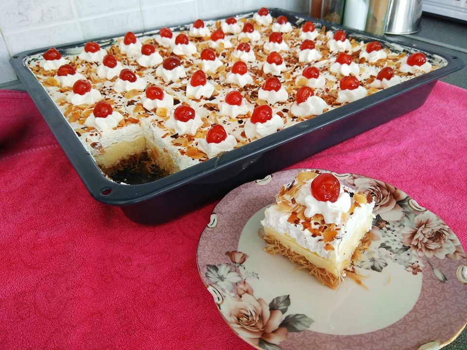 εκμεκ Ένα μεγάλο τετράγωνο ταψί με εκμέκ κανταΐφι, που δείχνει το χρυσαφένιο κανταΐφι στη βάση, μια παχιά στρώση λευκής κρέμας στη μέση και μια στρώση σαντιγί από πάνω, πασπαλισμένη με αμύγδαλο φιλέ.