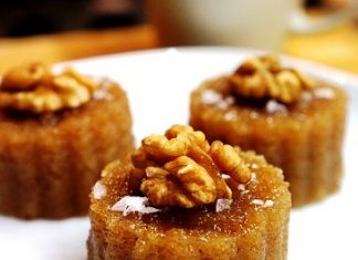 Σκούρος χρυσός σιμιγδαλένιος χαλβάς κομμένος σε ομοιόμορφα κομμάτια πασπαλισμένος με κανέλα και καρύδια