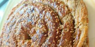 Χρυσαφένια στριφτή ταχινόπιτα σε σχήμα σαλιγκαριού πασπαλισμένη με σουσάμι και περιχυμένη με σιρόπι μελιού