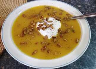 Μπολ με πορτοκαλί κολοκυθόσουπα βελουτέ γαρνιρισμένη με σπόρους κολοκύθας και μια κουταλιά γιαούρτι στο κέντρο