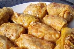 Λαχανοντολμάδες (γιαπράκια) σερβιρισμένοι σε πιάτο, με σάλτσα και τριμμένο μπούκοβο.