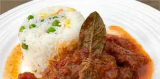 Ένα πιάτο με ζουμερό μοσχάρι κοκκινιστό σε κόκκινη σάλτσα, σερβιρισμένο δίπλα σε αφράτο ρύζι με πολύχρωμα λαχανικά.