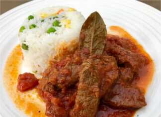 Ένα πιάτο με ζουμερό μοσχάρι κοκκινιστό σε κόκκινη σάλτσα, σερβιρισμένο δίπλα σε αφράτο ρύζι με πολύχρωμα λαχανικά.