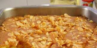 Ρεβανί Κομμάτια σιροπιαστό ρεβανί σε σχήμα ρόμβου, στολισμένα με ένα λευκό αμύγδαλο στην κορυφή μέσα στο ταψί