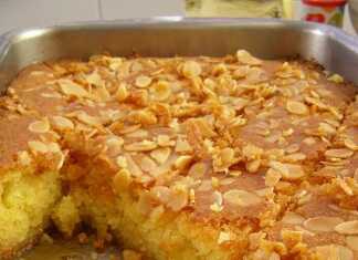 Κομμάτια σιροπιαστό ρεβανί σε σχήμα ρόμβου, στολισμένα με ένα λευκό αμύγδαλο στην κορυφή μέσα στο ταψί