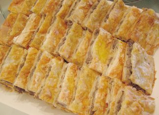 Τραγανή κιμαδόπιτα με χρυσαφένια σφολιάτα, πασπαλισμένη με σουσάμι, κομμένη σε τετράγωνα κομμάτια μέσα σε ταψί.