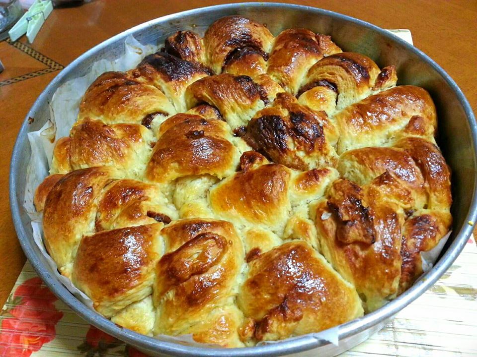 Σοκολατόψωμο Ένα στρογγυλό σοκολατόψωμο με τη γέμιση σοκολάτας να φαίνεται, σερβιρισμένο σε ταψι.