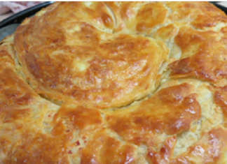 Μια χρυσαφένια, στριφτή τυρόπιτα σε ένα ταψί.