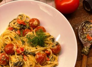 Μια πιατέλα με σπαγγέτι καλυμμένα με κρεμώδη πράσινη σάλτσα σπανακιού, κόκκινες πιπεριές και ολόκληρα ψημένα ντοματίνια που αχνίζουν